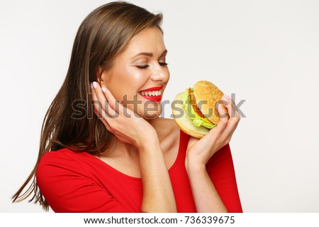 Smiling woman wearing red dress holding big burger. Isolated portrait.