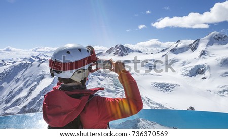 Skier take a smartphone photo at the summit