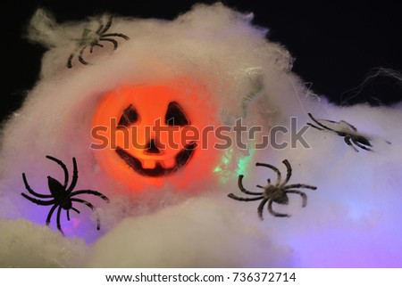 Spider and web with decorated pumpkin lantern with the light glowing in the dark background, Halloween scene and atmosphere 