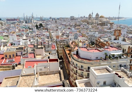 Aerial panoramic view of the old city rooftops and Cathedral de Santa Cruz from tower Tavira in Cadiz, Andalusia, Spain, an ancient port city, built on a strip of land surrounded by the sea.