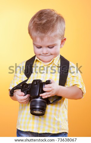 Little smiling photographer watching photo on professional camera