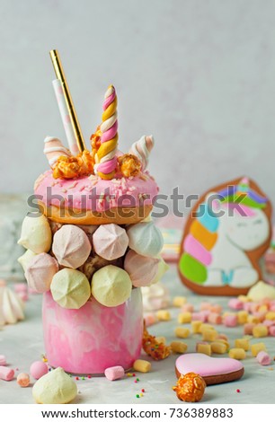 Happy Birthday party background: Freak shake topping with donut, marshmallow decorated as unicorn on the grey background; selective focus. 
