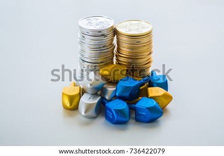 2 stacks of gold and silver Hanukkah coins surrounded by tiny dreidels isolated on solid background
