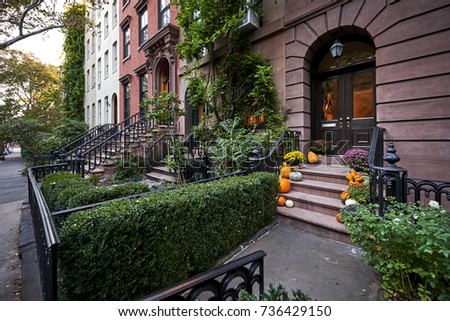 a colorful brownstone building with pumpkins on the steps in an iconic neighborhood of Manhattan, New York City.