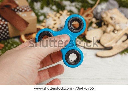 Hand with Spinner on white wooden table with christmas decoration