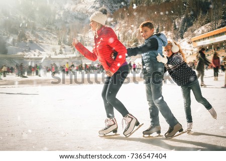 Happy family outdoor ice skating at rink. Mother and children has winter activities. Mom, kids. Medeo stadium. Almaty.