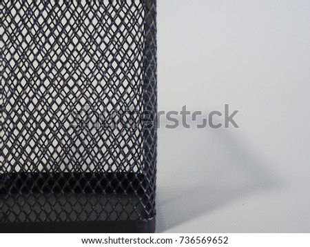 A side view of square shape 3D black container with thin black metal net on white background