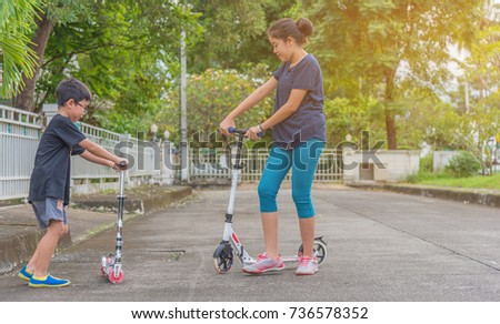image of Asian boy and girl playing scooter on street