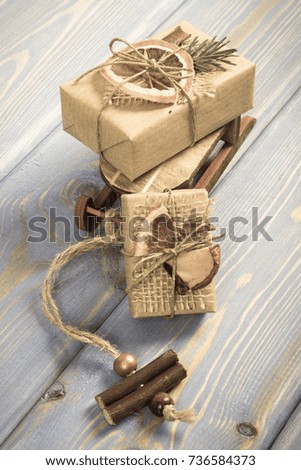Aged photo, Wooden sled, wrapped gifts with string and decoration for Christmas or other celebration lying on old boards