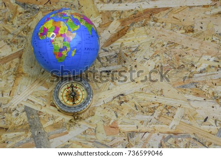 Compass and world globe atlas on wooden background. Selective focus.