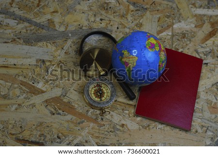 Travel guide concept. World globe atlas, passport and compass isolated on wooden background. Selective focus.