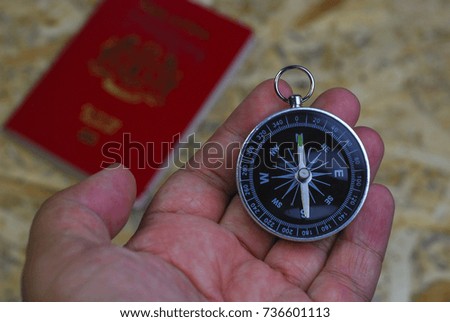 Travel guide concept. Hand holding tool for searching map destination. Selective focus on wooden background.