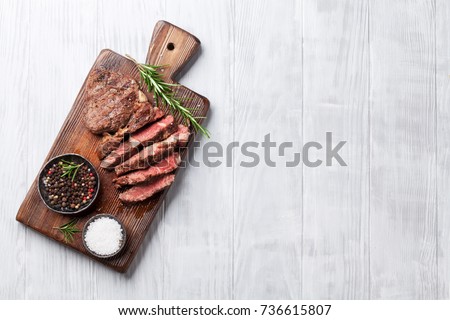 Grilled beef steak with spices on cutting board. Top view with copy space Royalty-Free Stock Photo #736615807
