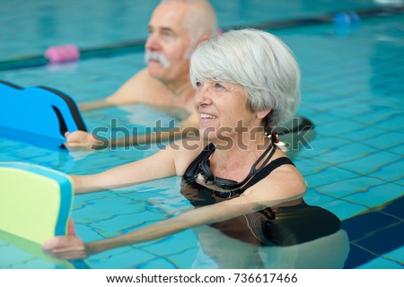 happy senior couple taking swimming lessons