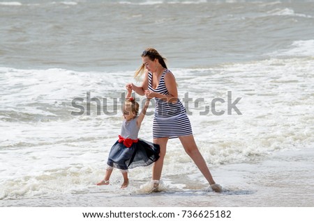 Mother and daughter walk on the beach.
