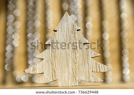 Wooden Christmas tree on wooden table, reflections on background, Christmas chains