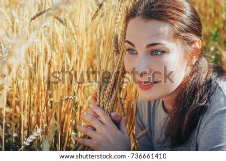 Portrait of a nice woman on a field full of yellow ears