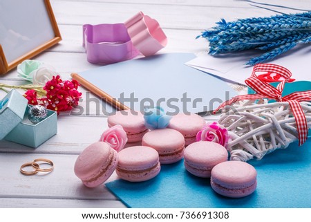 Pink macaroons. Wedding subject. wedding rings. postcard with pencil over white wooden background