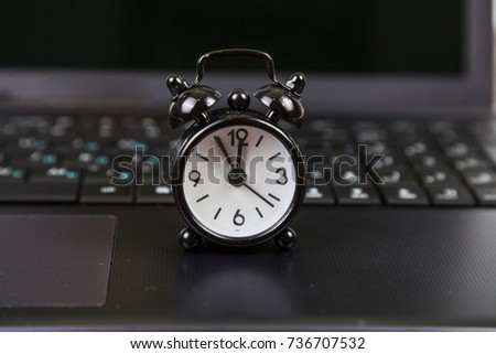 Black alarm clock on laptop.Time for business or the Internet.