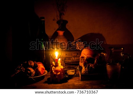Human skull and candle with  on wooden floor and old dirty wall  background, and vase flower,and glass,and bottle of wine, still life concep