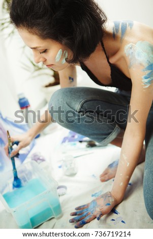 Woman sits in pofile and works on watercolor painting