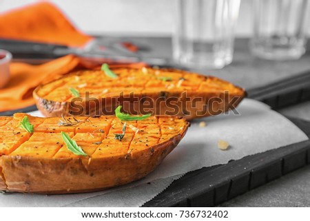 Cutting board with baked sweet potato on table, closeup