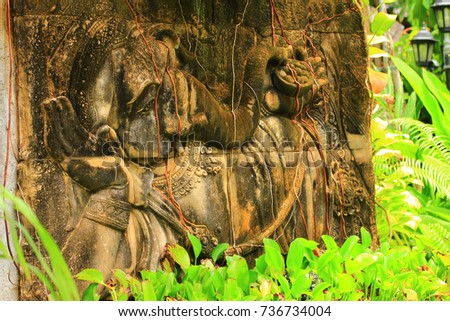 exotic old bas-relief in the jungle with a picture of a resting elephant and roots of the plants down on the surface of the bas-relief