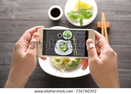 Woman taking photo of delicious food with mobile phone
