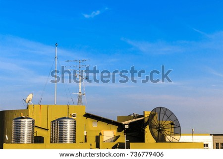 lightning rod, satellite dish,televisions antennas,stainless steel tanks on Roof top balcony on blue sky cloudy background.