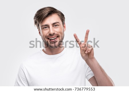 handsome smiling man showing victory sign, isolated on white