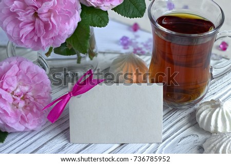 Peonies flowers pink glass of tea with card marshmallow on a white wooden background - stock image