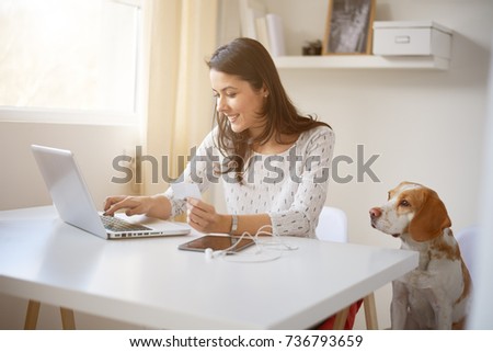 Young Caucasian businesswoman using credit card for on line payment. her dog next to her