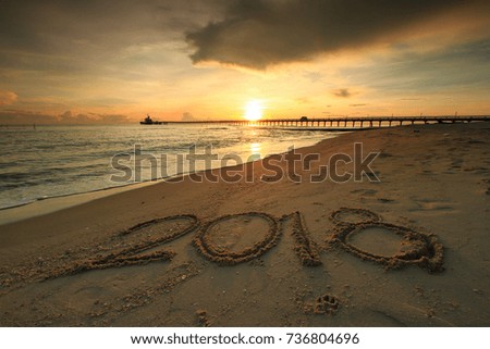 New Year 2018 is coming concept - inscription 2017 and 2018 on a beach sand, the wave is starting to cover the digits 2017 Royalty-Free Stock Photo #736804696