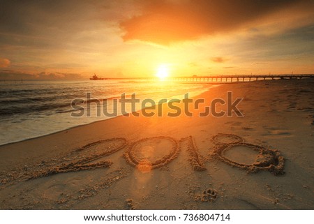 New Year 2018 is coming concept - inscription 2017 and 2018 on a beach sand, the wave is starting to cover the digits 2017 Royalty-Free Stock Photo #736804714