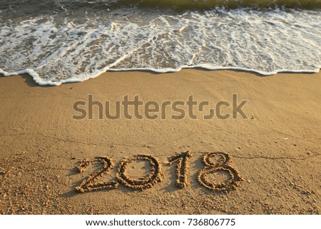 New Year 2018 is coming concept - inscription 2017 and 2018 on a beach sand, the wave is starting to cover the digits 2017 Royalty-Free Stock Photo #736806775