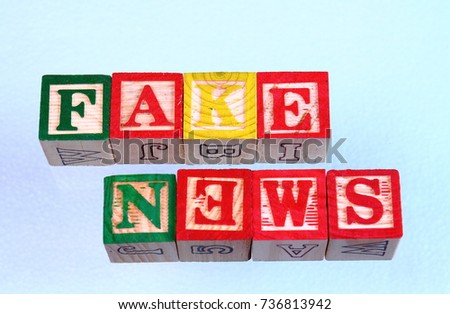 The term fake news displayed visually but spelled wrong on a clear background using colorful wooden toy blocks in landscape format with copy space