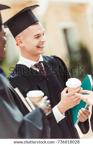 graduated happy multiethnic students with disposable cups of coffee