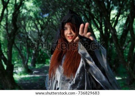 Witch in cloak at forest