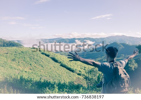 Mountain summit. Happy man gesture raised arms. Funny hiker with raised hands in the air on rock edge in national park. Vivid and strong vignetting effect.