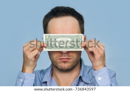A man holds a U.S. 1 one dollar. The guy holds up a one dollar bill before my eyes. see through money. hiding behind money. verification of bills