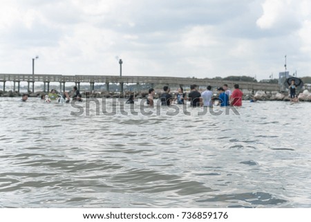 Blurred image crowd of people enjoy swimming, playing near fishing pier