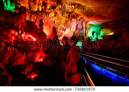 Tourist couple in underground cave Sataplia with colorful illumination in Kutaisi, Georgia