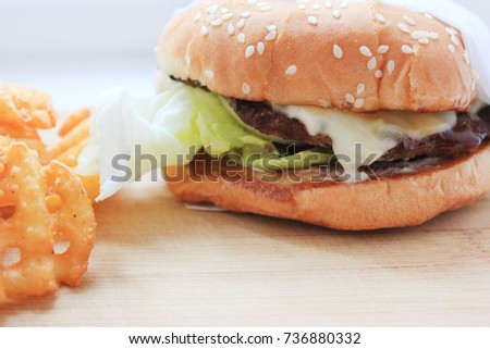 Fast Food Meal with Burger and Fries on Wooden Board Plate, White Background. Classic cheeseburger with lettuce, homemade sauce and side of french fries. Closeup picture, empty copyspace at the bottom