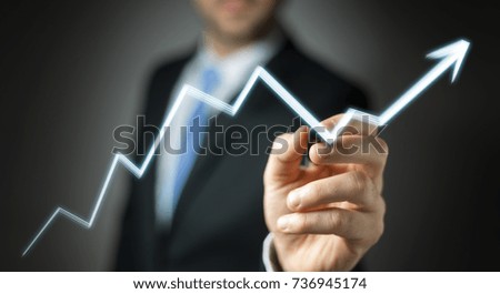 Businessman on blurred background drawing hand-drawn arrow going up