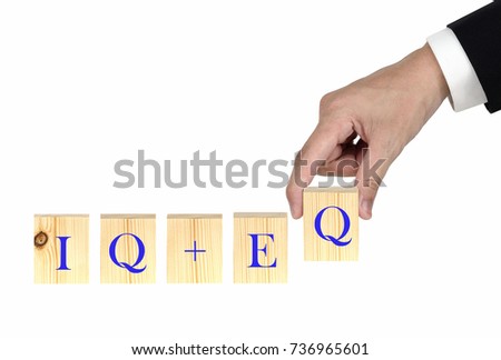 IQ + EQ = Success - wood word on white background with human finger at letter Q. Businessman in hand