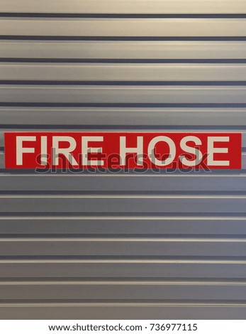 Red Fire Hose Sign on Metal Wall Background in Building For Fire Safety.