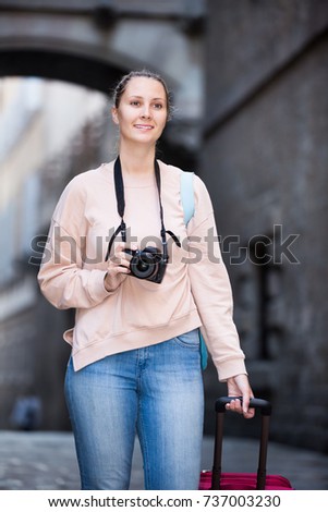 Young girl holding a camera in hands and photographing in city 