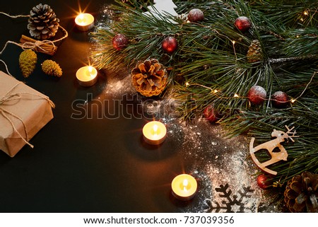 Christmas. Xmas toys, burning candles and spruce branch on black background top view. Space for text