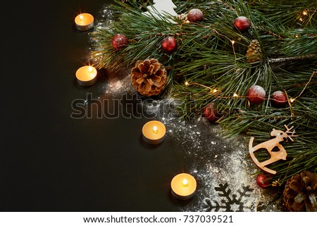 Christmas. Xmas toys, burning candles and spruce branch on black background top view. Space for text