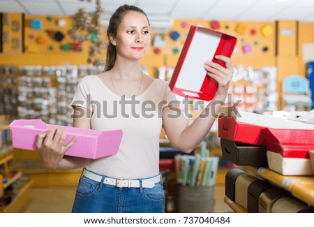 Female choosing multi colored and other gift boxes at shop and smiling
 